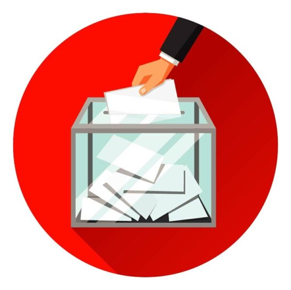 A hand dropping a ballot into a ballot box for votes and referendums